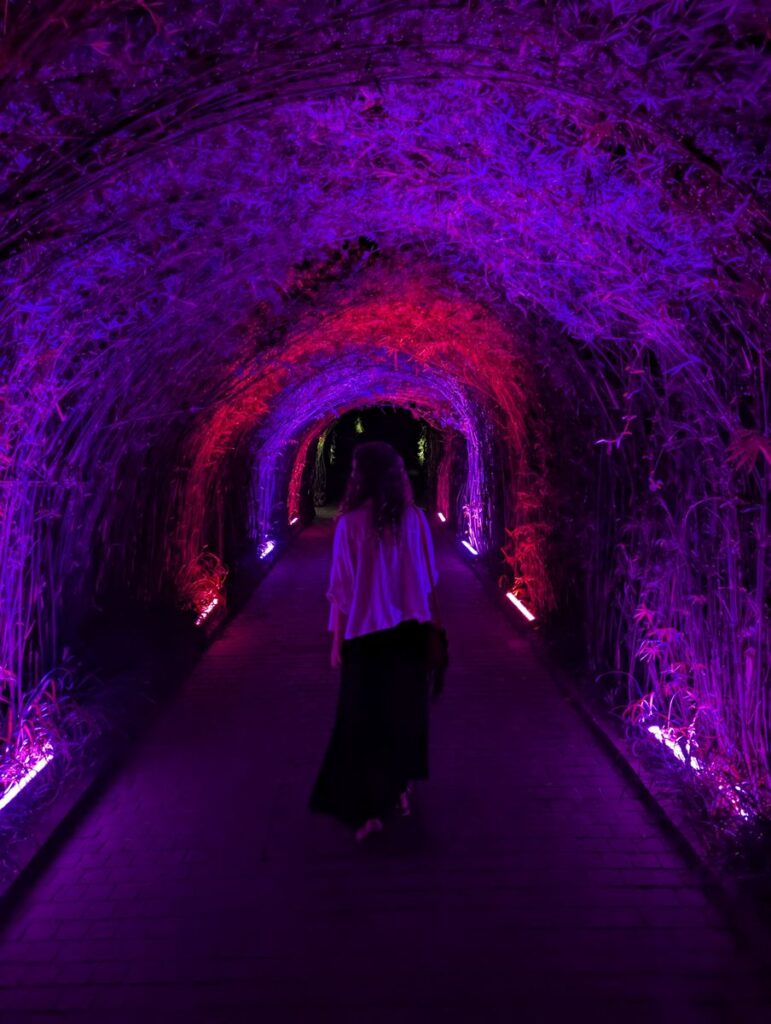 Aurélie de Lili Foodies Travel dans le tunnel lumineux violet et rouge à la sortie de Seven Paintings Ubud au Kaamala Resort Bali